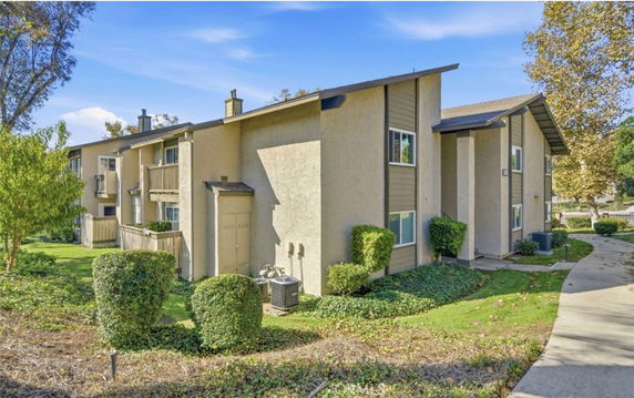 Front view of a two-story residential building with balconies and a walkway.