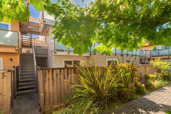 Front view of a two-story residential building with glass balconies and a wooden staircase.