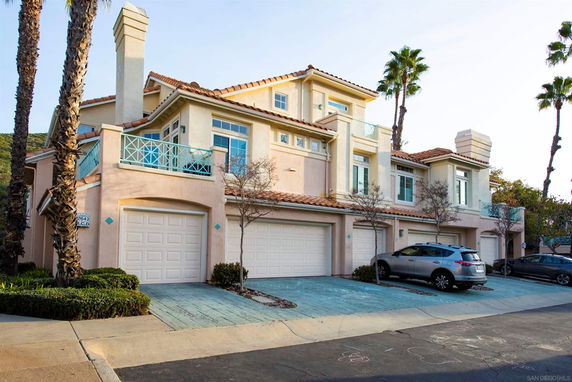 Front view of a multi-story house with garages and balconies.