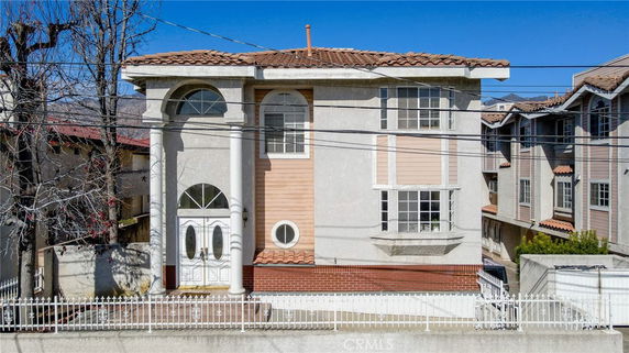 Front view of a two-story house with white columns and a tiled roof.