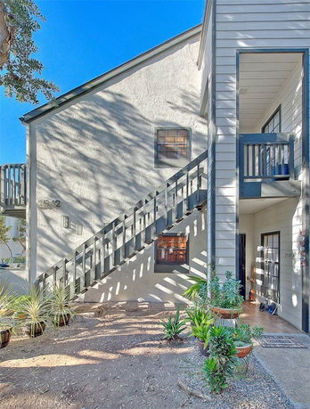 Front view of a two-story building with an outdoor staircase and small garden area.