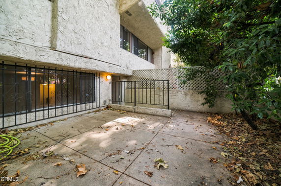 Patio area with concrete flooring and adjacent building structure with barred windows.