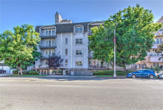 Front view of a multi-story residential building with balconies and a chimney.