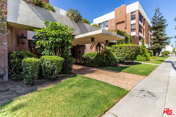 Front view of a multi-story apartment building with a landscaped entrance.