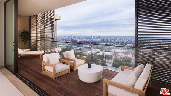 Spacious balcony with outdoor seating and panoramic view of the city.