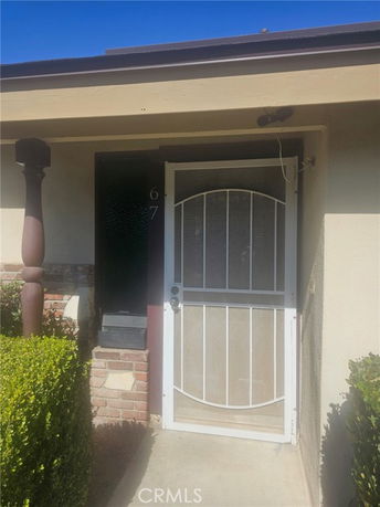 Front entrance of a house with a metal security door and partial brick detail.