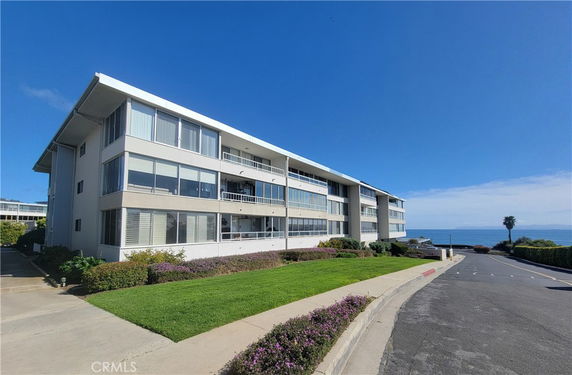 Front view of a multi-story building with large windows facing the ocean.