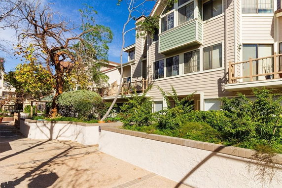 Front view of a multi-story residential building with balconies and surrounding greenery.