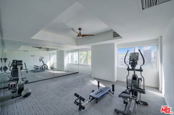 Indoor gym area with exercise equipment and large mirrors on the wall.