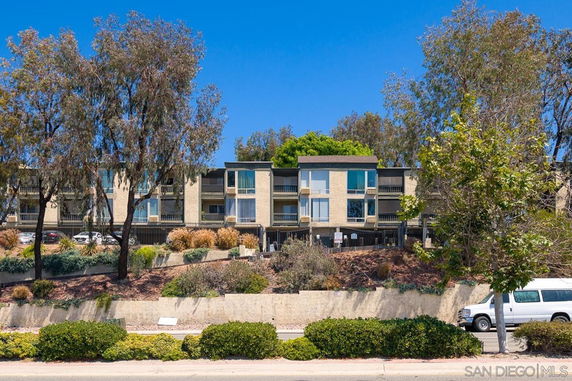 Front view of a multi-story apartment building with balconies and large windows.