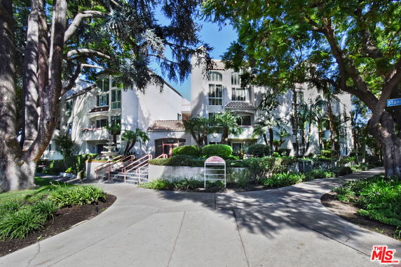 Front view of a multi-story apartment building with a landscaped entrance.