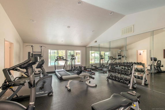 Indoor gym with exercise equipment and mirrored walls.