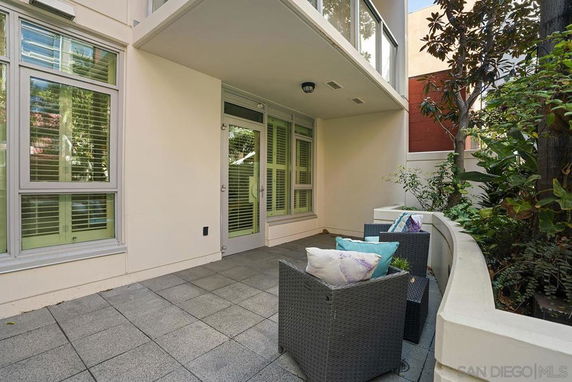 Outdoor patio area with chairs and a view of residential building windows.
