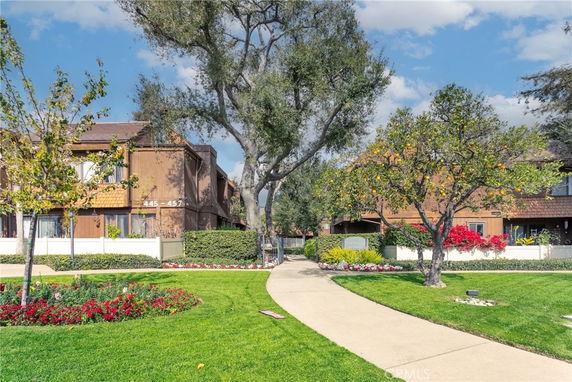 Front view of a two-story residential building surrounded by trees and landscaped gardens.
