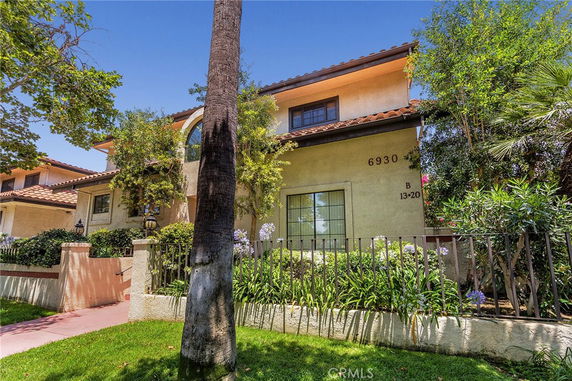 Front view of a two-story house with a tiled roof and decorative plants.