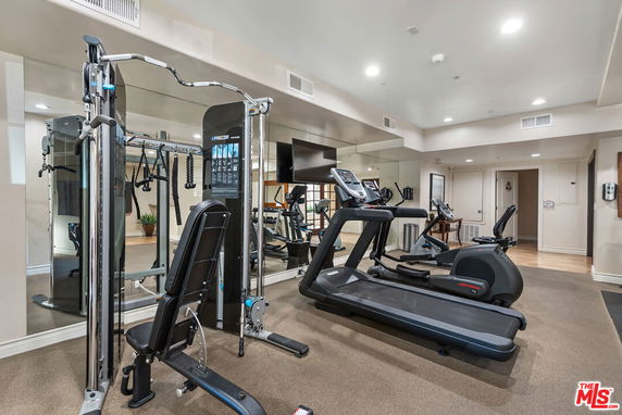 Indoor gym area with exercise equipment including a treadmill and weight machine.