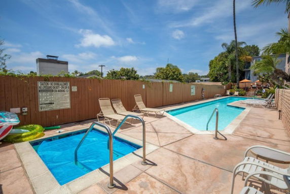 Outdoor swimming pool area with lounge chairs and a wooden fence.