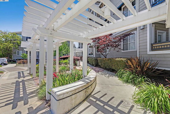 Front view of a residential building with white pergola and landscaping.