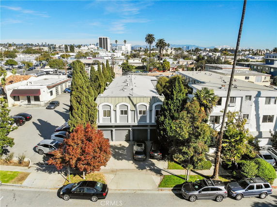 Aerial view showing a multi-story building with parking and adjacent structures.