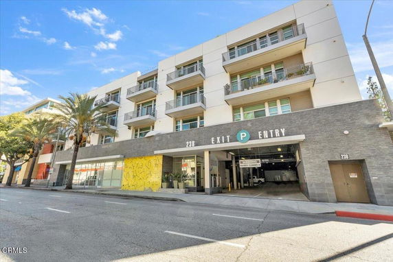 Front view of a multi-story building with balconies and a parking entry.