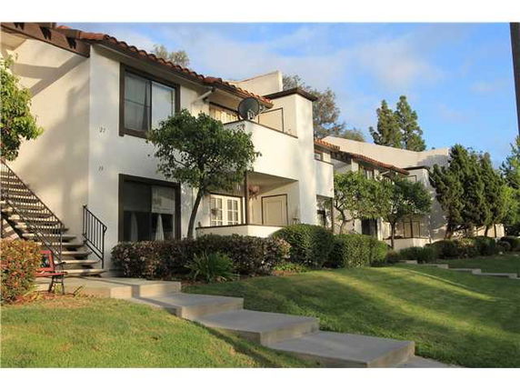 Front view of a two-story apartment building with a staircase and landscaped lawn.
