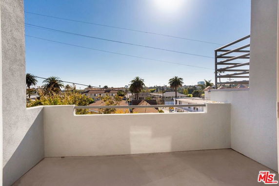 Balcony view overlooking surrounding residential area with palm trees.