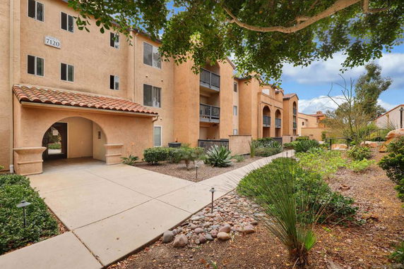 Front view of a multi-story apartment building with balconies and an archway entrance.