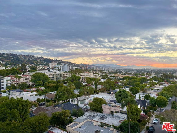 Panoramic view of a residential area with various buildings and greenery at sunset.