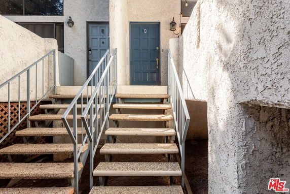 Front view of a building entrance with two staircases and blue doors.