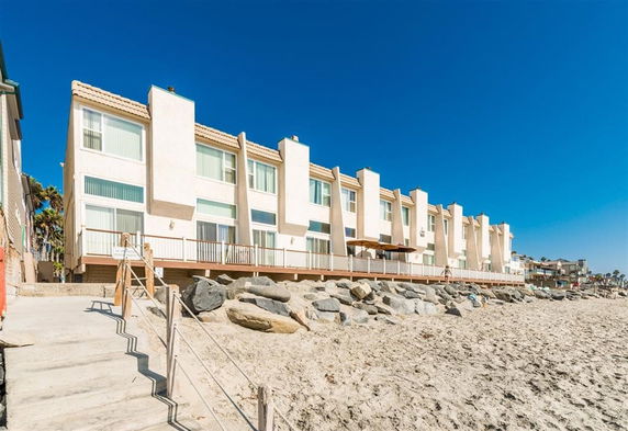 Front view of a multi-story beachfront building with large windows and balconies.