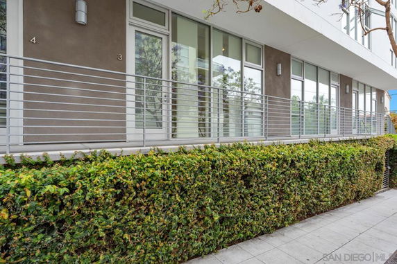 Front view of a modern apartment building with large windows and metal railings.