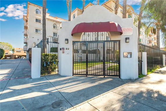 Front view of a multi-story apartment building with gated entrance.