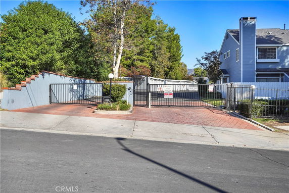 Front view of a house with a gated driveway and brick pavement.