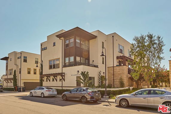 Front view of a modern multi-story apartment building with large windows and balconies.