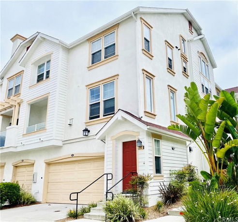 Front view of a multi-story house with a garage and red entrance door.