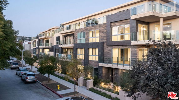 Front view of a modern multi-story apartment building with large windows and balconies.