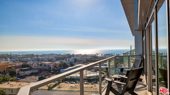 View from a high-rise balcony overlooking a coastal city and ocean.