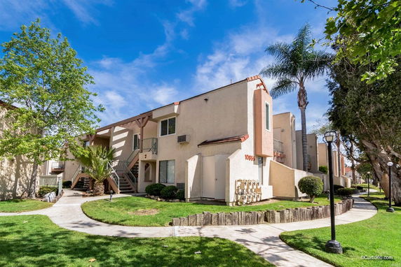 Front view of a two-story residential building with exterior staircases and landscaping.