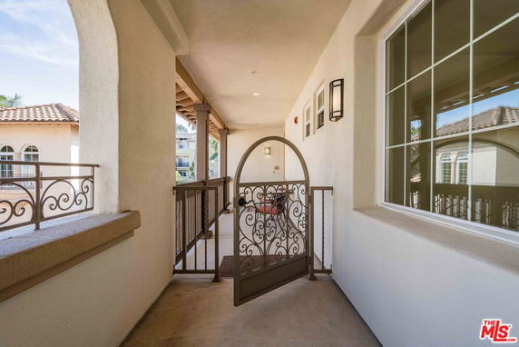 Exterior view of a building corridor with arched doorways and a decorative gate.