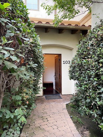 Front view of a house with an arched entrance and the number 103 on the wall.