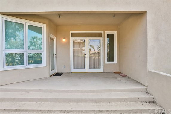 Front view of a building entrance with a covered porch and glass doors.