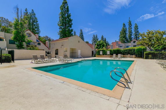 Outdoor swimming pool area with surrounding residential buildings.