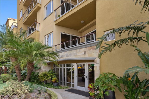 Front view of a multi-story building with balconies and glass entrance.