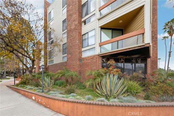 Front view of a multi-story brick and stucco building with balconies and large windows.