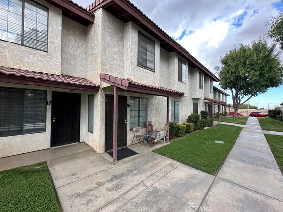 Front view of a multi-story townhouse with a shared walkway and small porches.