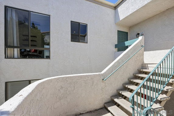 Exterior view of a building with stairs leading to an upper level entrance.