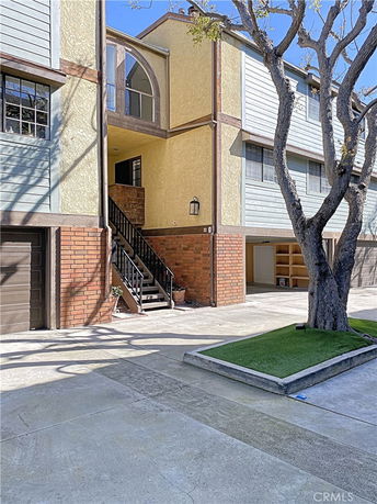 Front view of a townhouse with brick and wood exterior, featuring a staircase and entryway.