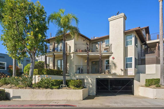 Front view of a multi-story residential building with balconies and a ground-level garage entrance.