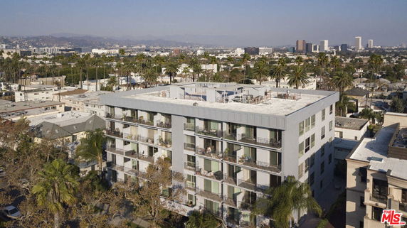Front view of a multi-story apartment building with balconies in a city setting.