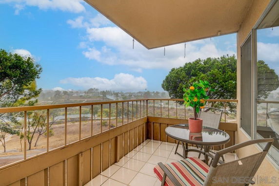 Balcony with table and chairs overlooking natural landscape and distant scenery.